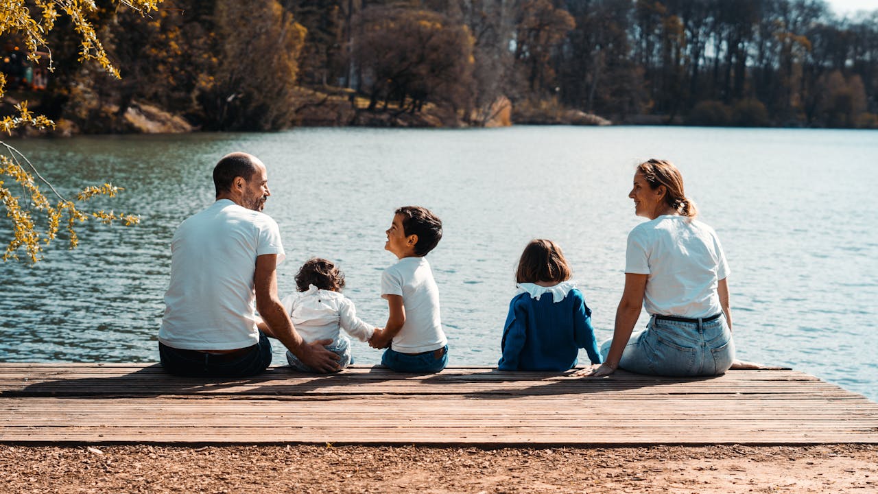 A family of five relaxing by a serene lake in Lyon, France on a sunny day.